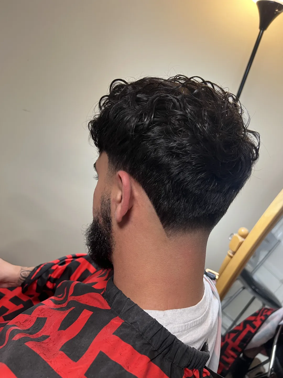 Low taper fade with textured curly crop and lined beard — cut at Studio K, Guelph